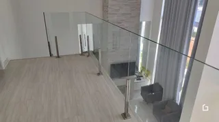 Ambiente interno com piso de madeira clara e divisória de vidro.