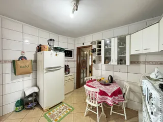 Interior de uma cozinha com armários brancos e área de jantar em Lajeado.