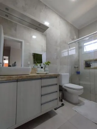 Foto de um banheiro com bancada e box de vidro em um imóvel.