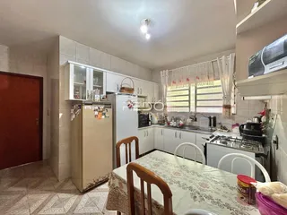 Cozinha e sala de jantar com armários brancos e mesa de jantar de madeira.