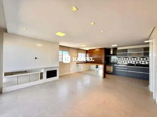 Sala de estar com piso claro e área de cozinha moderna.