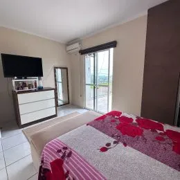 Quarto com cama e televisão instalada na parede.