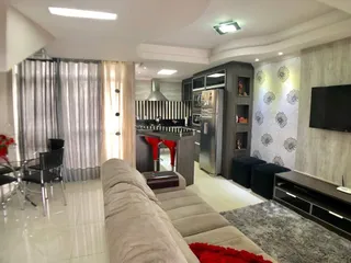 Uma sala de estar com sofá e televisão montada na parede.