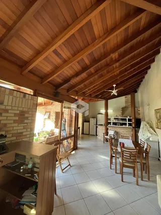 Interior de uma sala de estar com teto de madeira e paredes de tijolo.