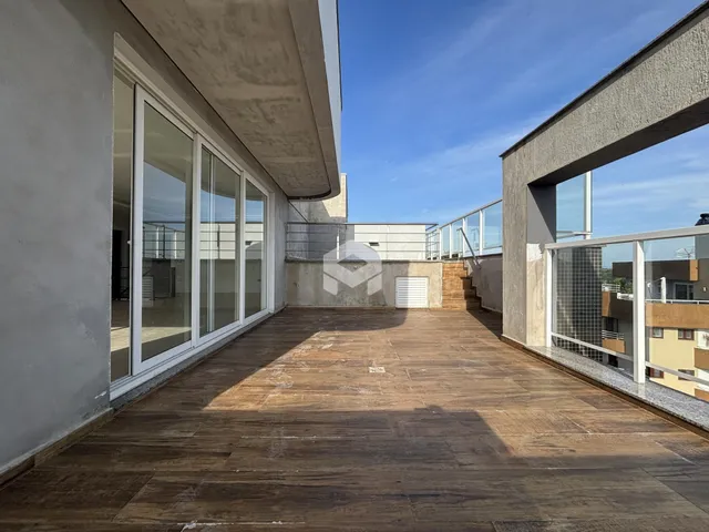 Área externa pavimentada com piso de madeira e portas de vidro de uma residência.