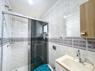 Foto de um banheiro com box de vidro e revestimento cerâmico.