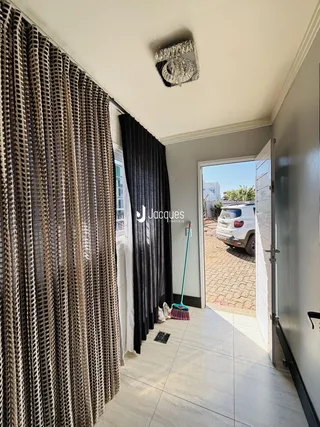 Vista de um corredor interno com cortinas escuras e porta de entrada para o exterior.