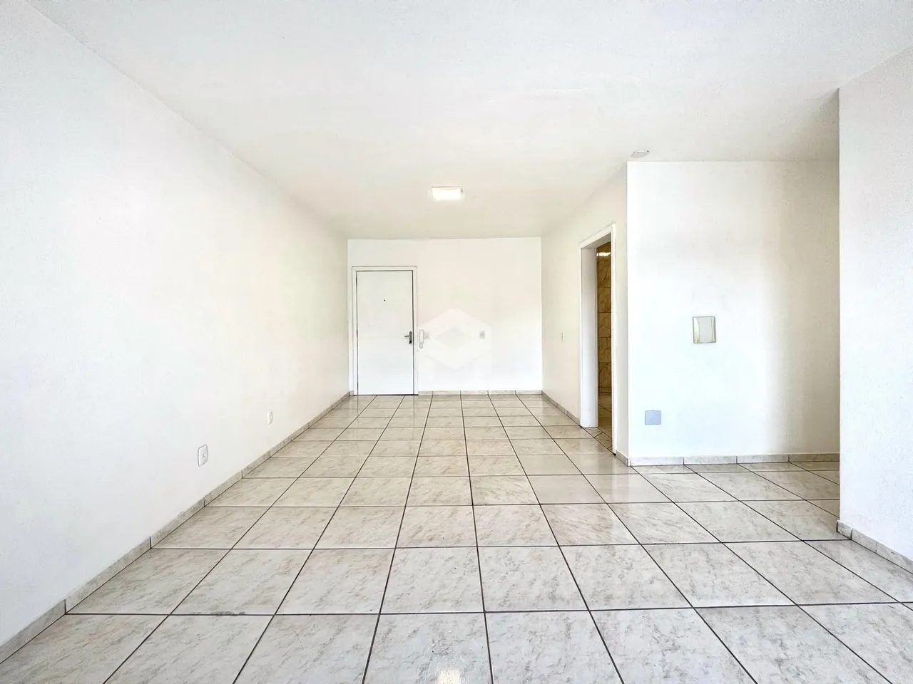 Corredor interno com piso de cerâmica e paredes brancas.