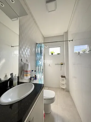 Banheiro moderno com revestimento branco e bancada escura.
