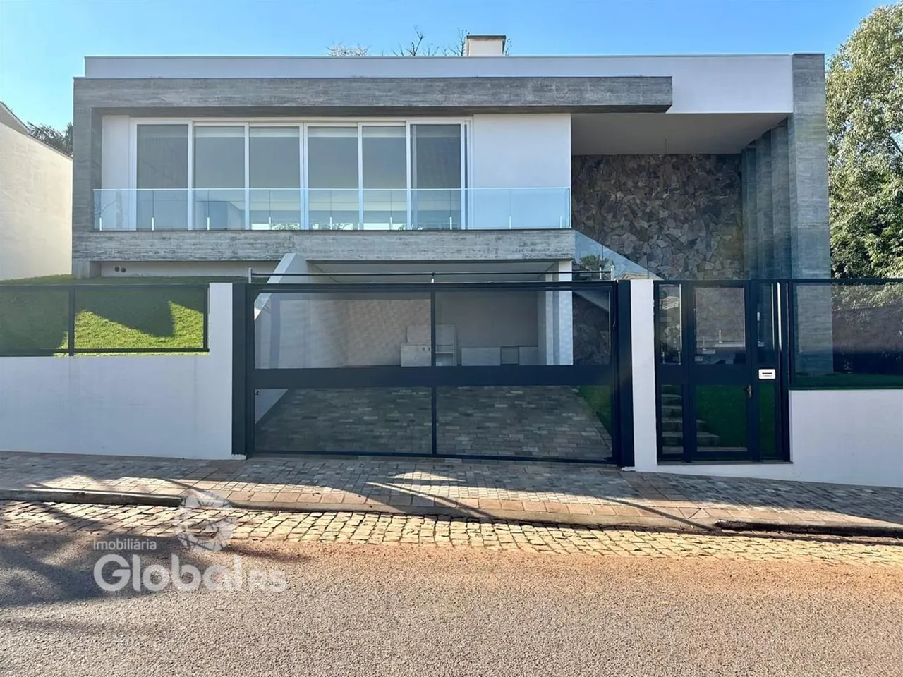 Fachada moderna de uma residência em Lajeado, Brasil, com portão e muro.