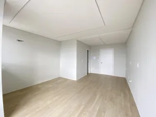Hall de entrada com piso de madeira clara e paredes brancas.