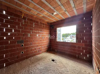 Interior de um cômodo com paredes de tijolo aparente e piso de terra.