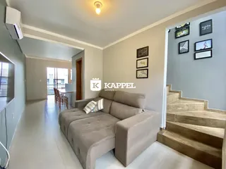 Sala de estar com um sofá grande e decoração de parede em um apartamento.