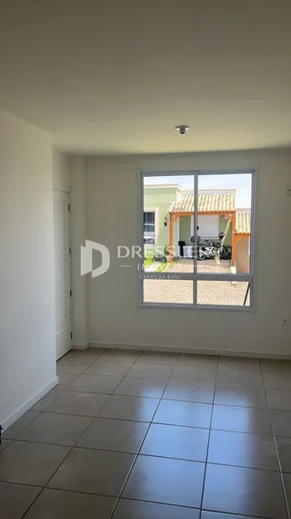 Interior de uma sala com piso de cerâmica e grande janela.