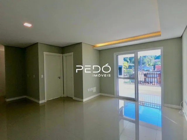 Sala de estar com piso claro e porta de vidro que dá para o exterior.
