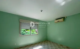 Vista interna de uma sala com paredes verde-água e uma janela.