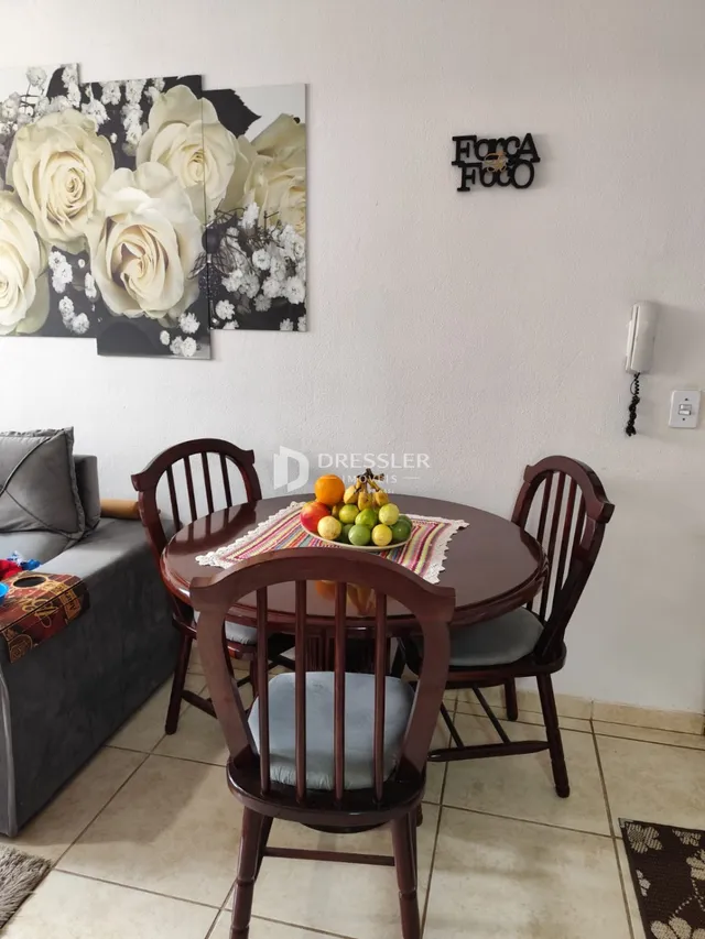 Uma mesa de jantar de madeira com cadeiras é visível na sala.