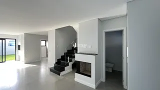 Hall de entrada com escadaria e parede de lareira em um imóvel.