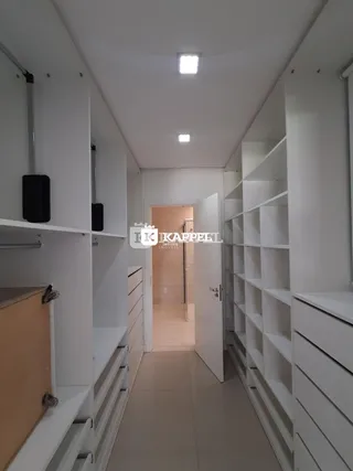 Corredor interno de um imóvel com armários brancos e piso claro.
