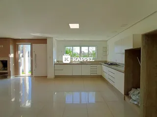 Sala de estar e cozinha com piso claro e armários brancos em um imóvel em Lajeado.