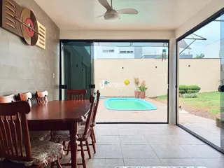 Uma sala de jantar interna se abre para uma área externa com piscina.