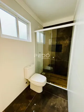 Foto de um banheiro com azulejos escuros e uma porta de vidro.