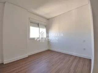 Uma sala com paredes brancas e piso de madeira clara.
