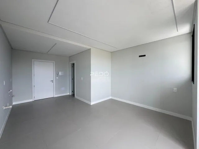 Vista interna de um ambiente com paredes brancas e piso cinza.