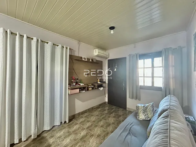 Sala de estar com paredes brancas e piso de cerâmica.