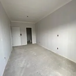 Foto de um corredor interno com paredes brancas e piso claro.