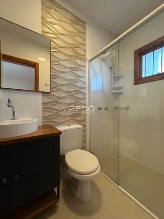Foto de um banheiro com box de vidro e vaso sanitário.