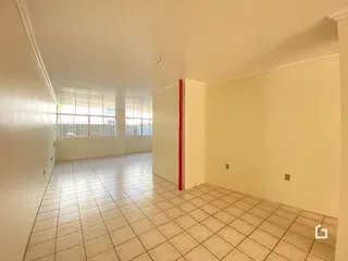 Corredor com piso de cerâmica e janelas ao fundo.