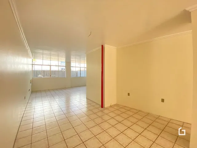 Corredor com piso de cerâmica e janelas ao fundo.