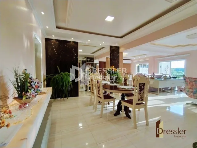 Sala de estar com mesa de jantar de madeira clara e piso de cerâmica.