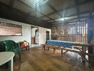 Interior de uma área comum com piso de madeira e vigas expostas.