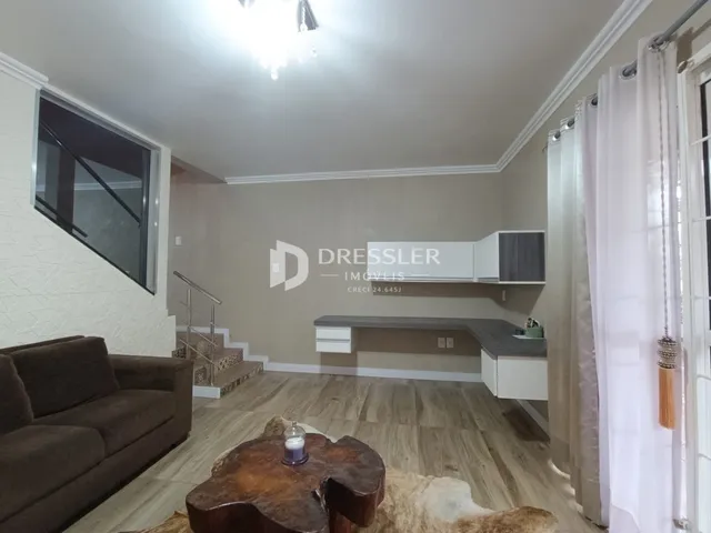 Sala de estar com piso de madeira clara e janela de grande porte.