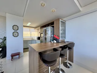 Vista de uma cozinha moderna com ilha e banquetas em um imóvel no Brasil.