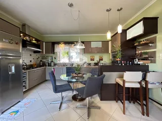 Cozinha e sala de jantar moderna com armários escuros e piso claro.
