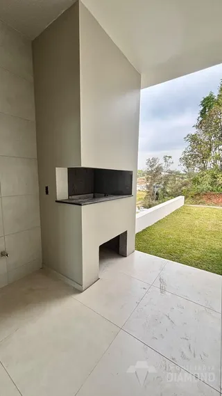 Vista interna de um espaço com piso de concreto e área externa gramada.