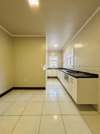 Interior de uma cozinha com piso de cerâmica e armários brancos.