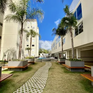 Vista externa de um jardim com caminho e bancos entre edifícios residenciais.