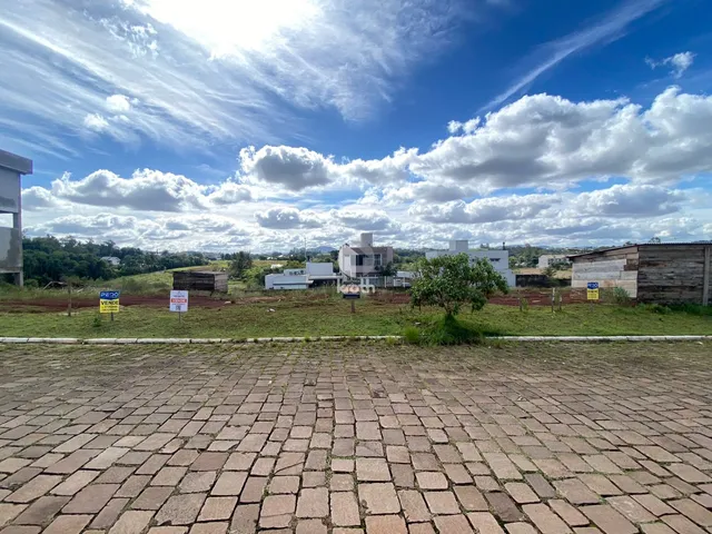 Vista externa de uma propriedade com gramado e área pavimentada.