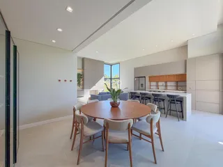 Uma sala de jantar ampla com mesa redonda e cozinha integrada.