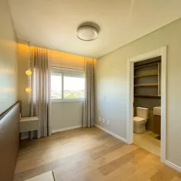 Ambiente interno com piso de madeira e janela iluminada.