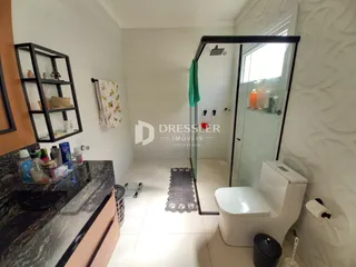 Interior de um banheiro com piso de cerâmica e box de vidro.