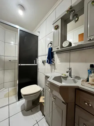Foto de um banheiro com revestimento cerâmico branco e louças sanitárias.