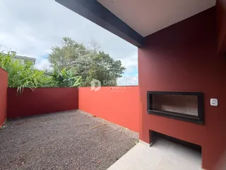 Parede externa vermelha de uma propriedade em Lajeado, Brasil, com área de terra batida.