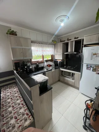 Vista interna de uma cozinha com armários e piso de cerâmica.