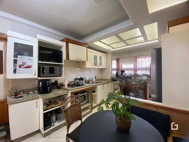 Interior de uma cozinha com armários brancos e bancadas claras.