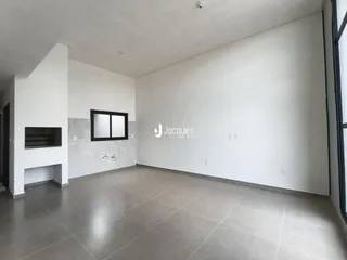 Ambiente interno de uma sala ampla com paredes brancas e piso de cerâmica.
